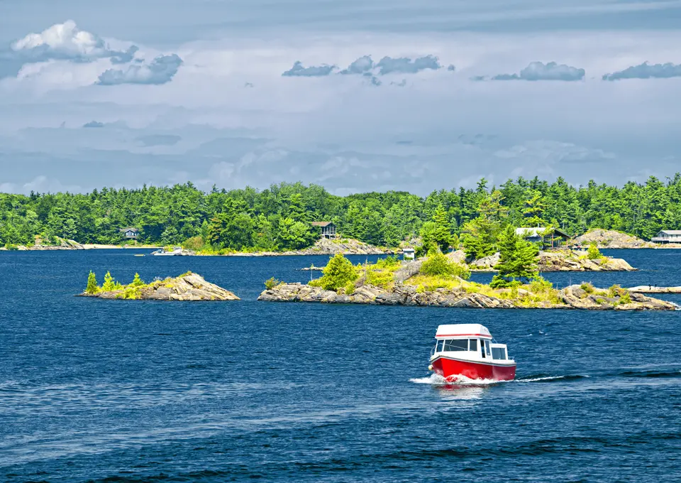 Boat passing rocky, pine-covered islands on a lake
