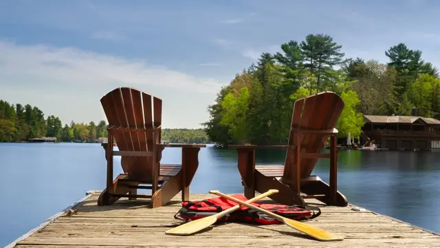 Two Muskoka chairs and paddles on a lake dock