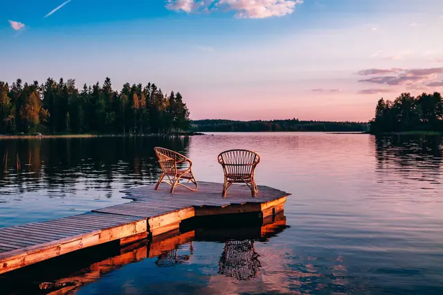 Two wicker chairs on a lake dock at sunset