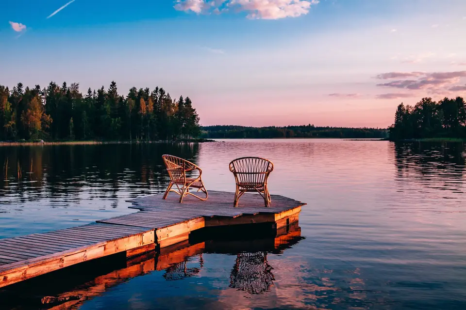 Two wicker chairs on a lake dock at sunset
