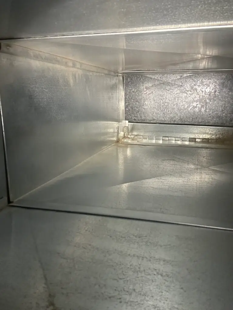 A clean, empty, rectangular metal duct with smooth, shiny surfaces and some light reflecting off the interior walls—ideal for improving indoor air quality through proper duct cleaning.